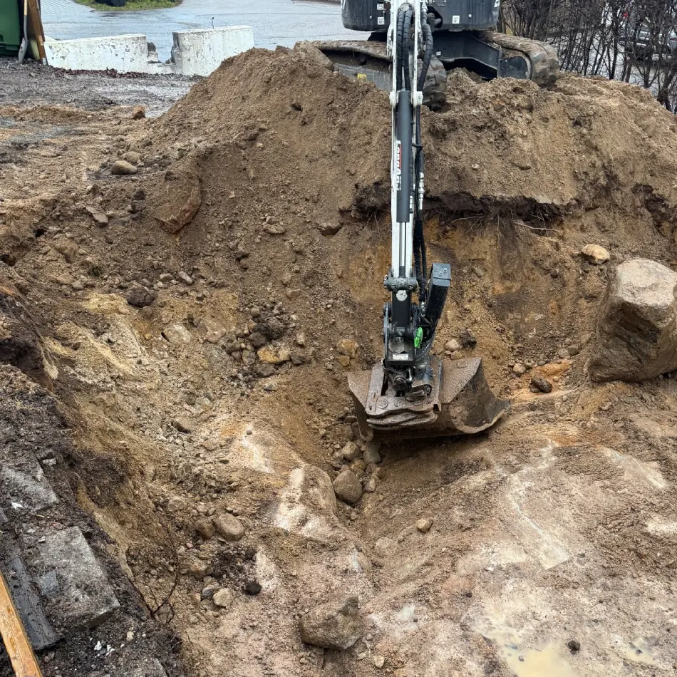 Schakt och transport i Bromma med grävmaskin på byggarbetsplats.